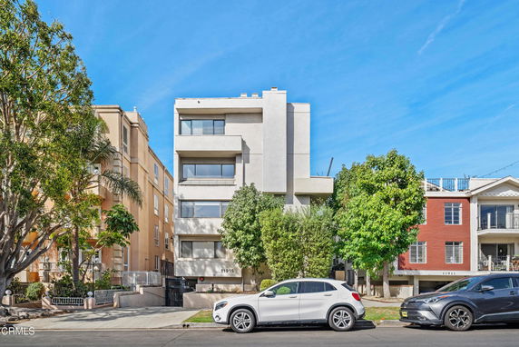 Front view of a multi-story building with balconies and a gated entrance.