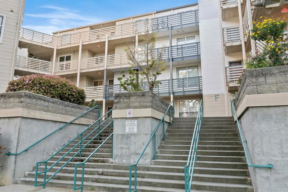 Front view of a multi-story apartment building with balconies and exterior stairs.