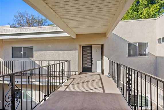 Exterior view of a multi-level building entrance with a metal railing and beige walls.