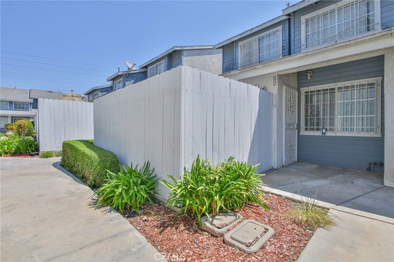 Front view of a townhouse with two stories and white fencing.