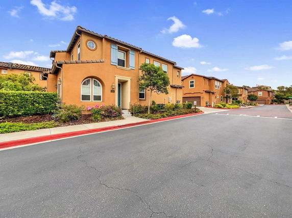 Front view of a two-story house with a stucco exterior and arched windows.