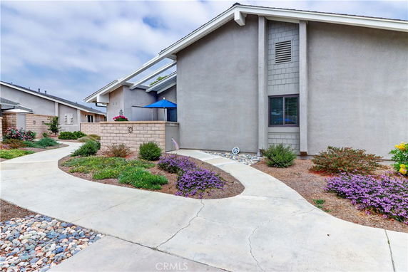 Front view of a single-story house with a sloped roof and walkway.