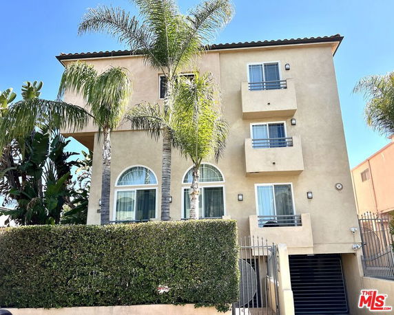 Front view of a multi-story building with balconies and arched windows.