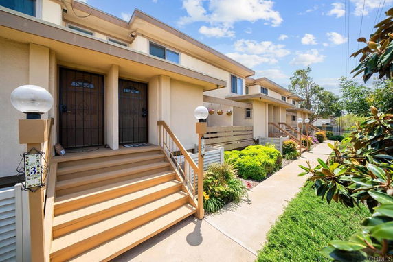 Front view of a multi-unit residential building with stairs leading to doorways.