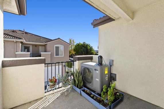 Rooftop with air conditioning unit and small plants in containers.