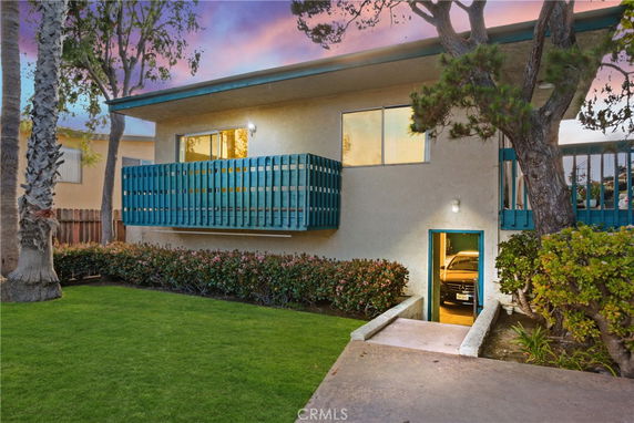 Front view of a two-story building with a balcony and an open garage.