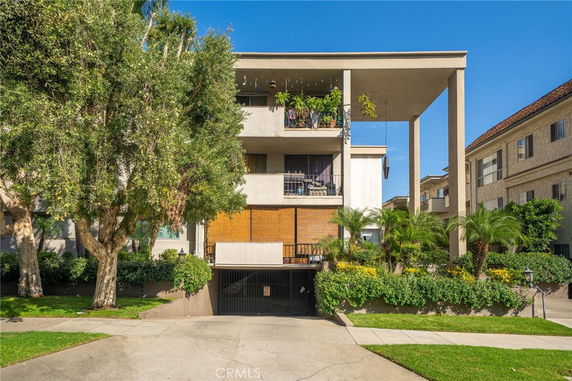 Front view of a multi-story apartment building with balconies and a garage entrance.