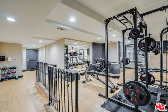 Indoor gym area with various exercise equipment, including weight racks, benches, and dumbbells.
