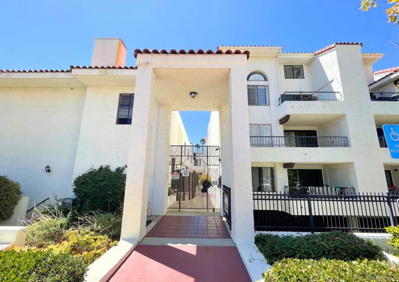 Front view of a multi-story residential building with gated entrance and balconies.