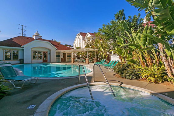 Outdoor swimming pool area with patio seating and surrounding greenery.