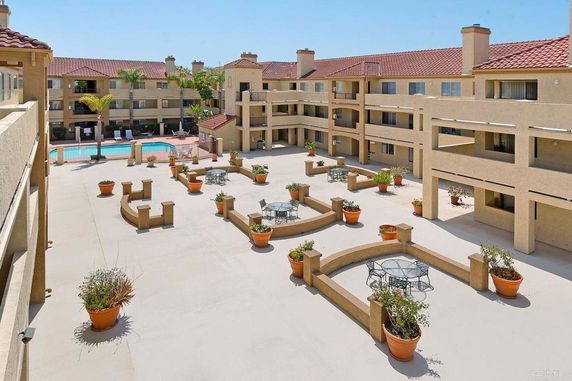 View of a multi-story residential complex with a swimming pool and courtyard area.