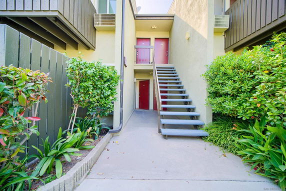 Front view of a multi-story building with external staircase and entrance door.
