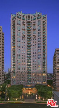Front view of a tall, multi-story residential building with balconies and a decorative entrance.
