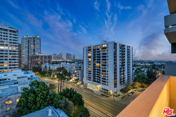 View of a cityscape with several multi-story buildings and busy streets at dusk.