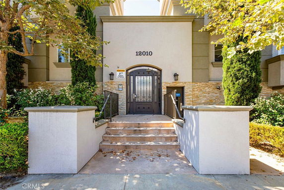 Front view of a multi-story building entrance with steps and iron gate.