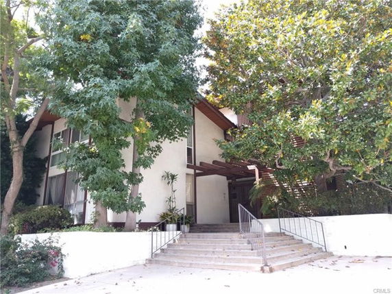 Front view of a multi-story building with a staircase leading to the entrance.
