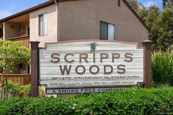 Front view of a condominium building with a sign that reads 'Scripps Woods, A Private Condominium Community.'