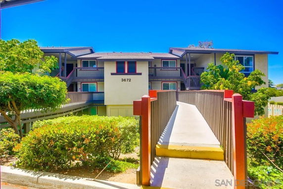 Front view of a two-story residential building with balconies and a walkway leading to the entrance.