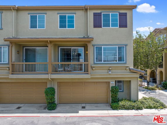 Front view of a two-story building with balconies and garages.