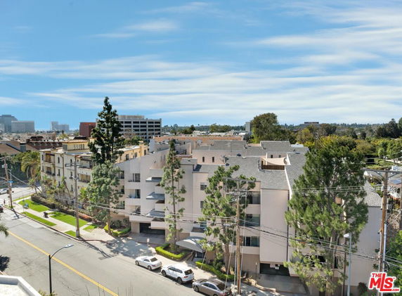 Elevated view of multiple apartment buildings with surrounding greenery and distant skyline.