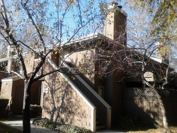 Front view of a two-story residential building with external stairs and chimney.