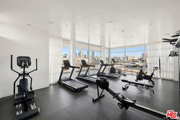 Indoor gym area with exercise equipment and large windows offering a view of the city skyline.