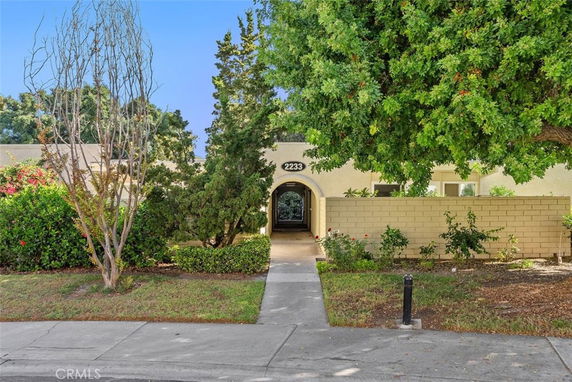 Front view of a house with an arched entrance and surrounding greenery.