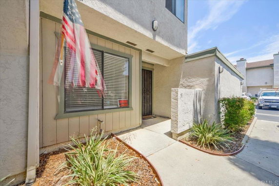 Front view of a house with an American flag and a small garden area.