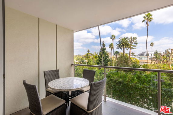 Balcony view with outdoor seating and surrounding trees.