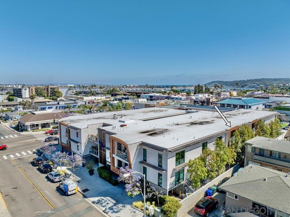 Aerial view of a flat-roofed building with multiple units in an urban area.