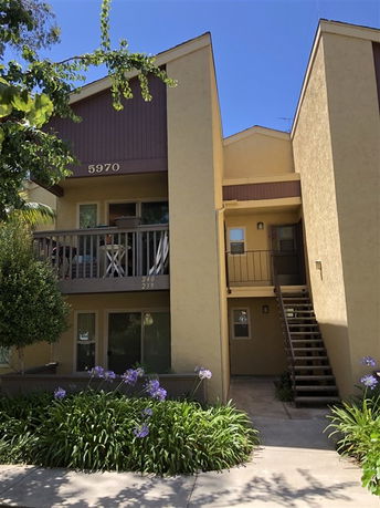 Front view of a two-story apartment building with balconies and an external staircase.
