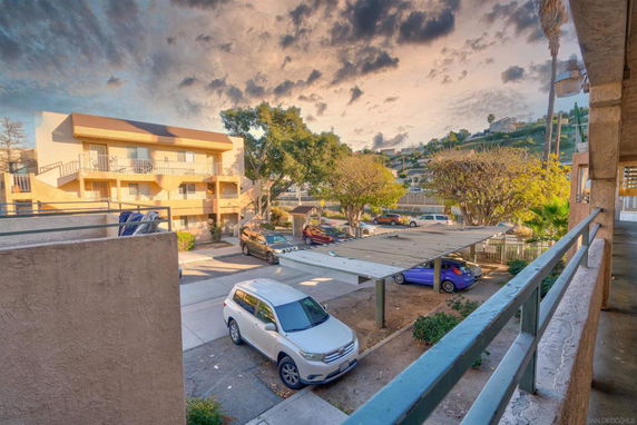 Outdoor parking area with multiple parked cars and a building in the background.