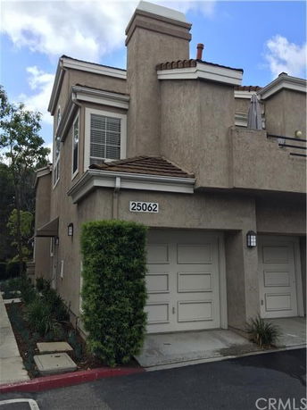 Front view of a townhouse with a garage and beige stucco exterior.