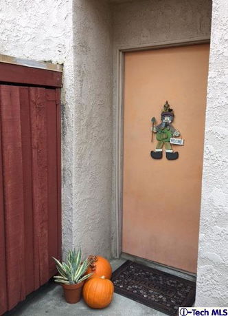 Front view of an entrance with a decorated door and pumpkins.
