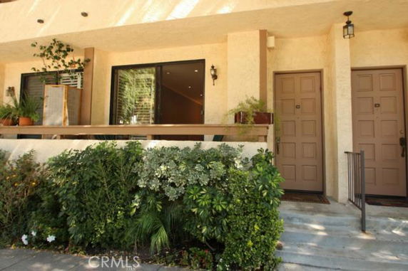 Front view of a building with two doors and a large window, surrounded by plants.