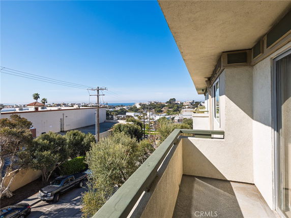 View from the balcony overlooking surrounding buildings and the sea in the distance.