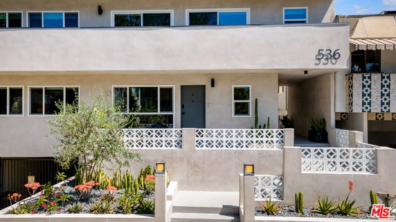 Front view of a modern two-story house with a balcony and decorative facade.