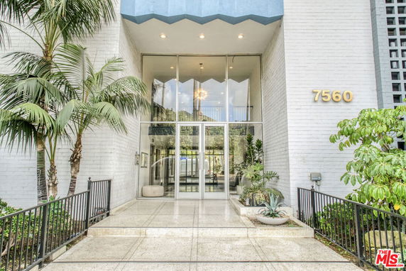 Front view of a building entrance with large glass doors and brick walls.