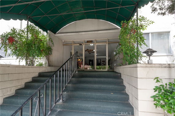 Front view of a building entrance with a covered staircase and glass doors.
