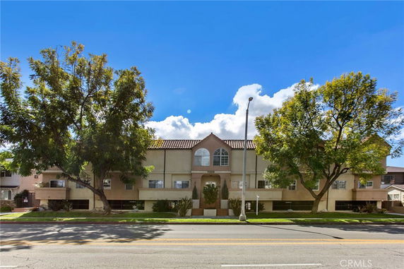 Front view of a multi-story building with large arched windows and a tiled roof.