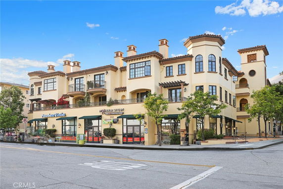 Front view of a multi-story building with commercial spaces on the ground floor and residential areas above.