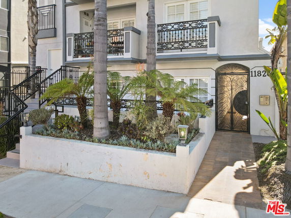 Front view of a multi-story building with decorative railings and a gated entrance.