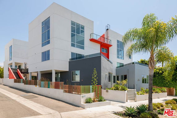 Front view of a modern three-story building with large windows and distinct geometric design.
