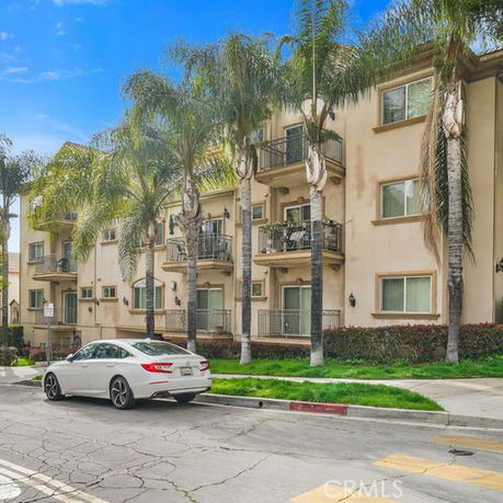 Front view of a multi-story residential building with balconies and palm trees.