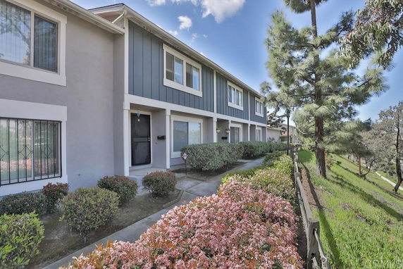 Front view of a two-story townhouse with bushes and a path leading to the entrance.