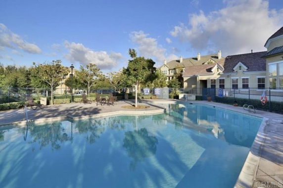Outdoor swimming pool area with surrounding buildings and trees.