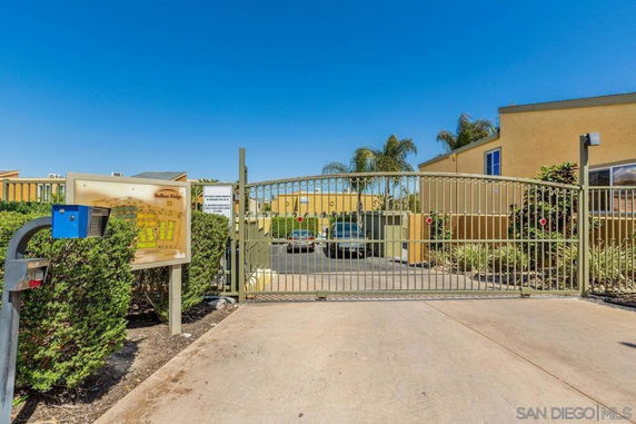 Entrance gate to a residential parking area with a metal gate and a directory sign.