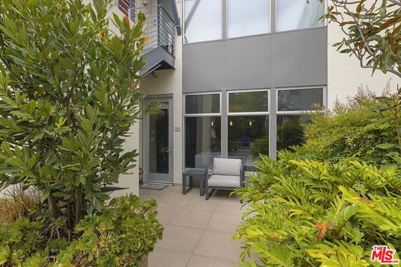 Front view of a building with large glass windows and patio seating.