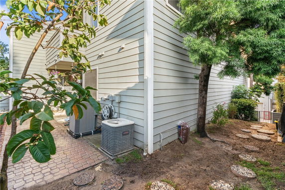 Side view of a two-story house with exterior siding and HVAC units.
