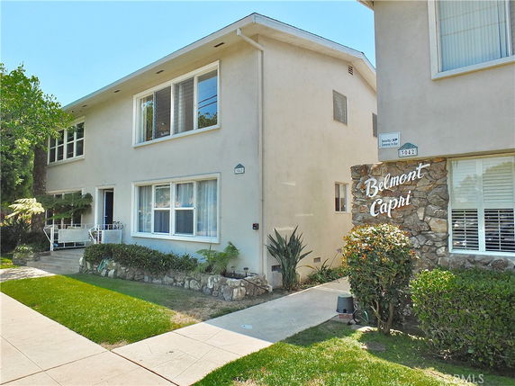 Front view of a residential building named Belmont Capri with large windows and a stone facade entrance.